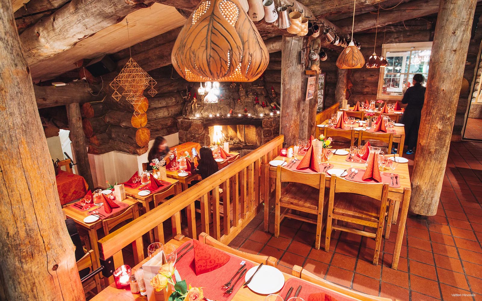 The traditional kelo restaurant with terracotta floor tiles and pine dining furniture in East Village at Kakslauttanen Resort in Finnish Lapland