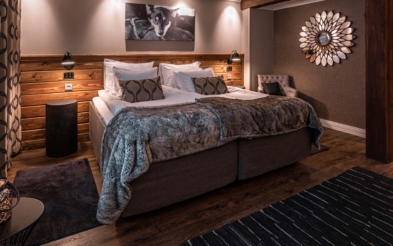 A cosy guest room at Beana Laponia in Lapland, Finland.  A cosy throw adjourns the comfortable bed and a picture of a husky take pride of place above the bed