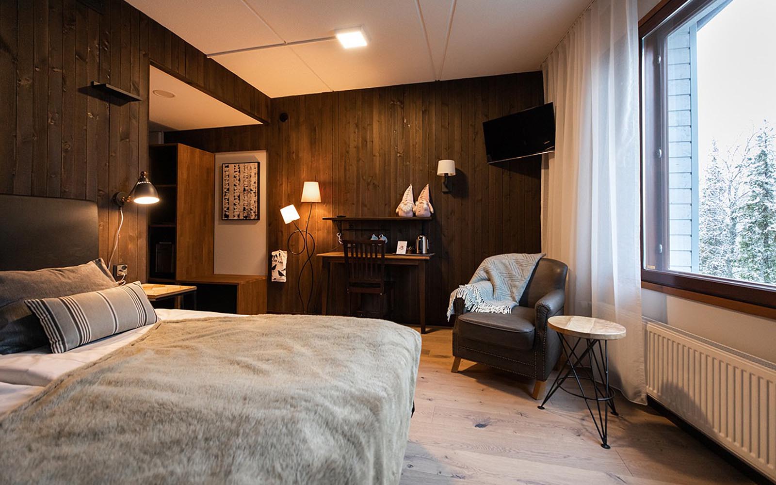 A standard guest room at Santa's Hotel Aurora in Luosto, Finland with neutral decor and a cosy faux fur throw on the bed