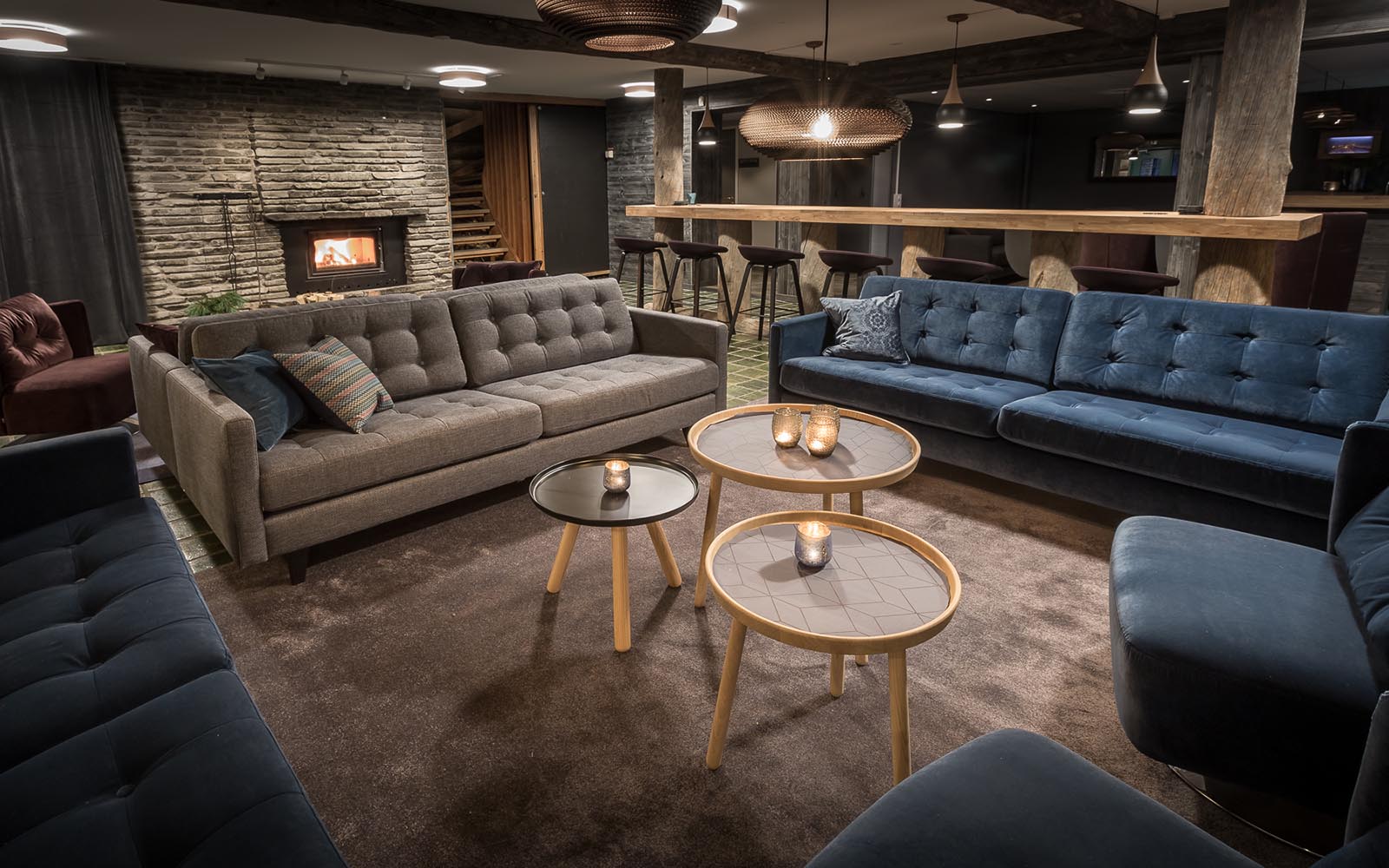 Large comfortable velvet sofas surround 3 small round coffee tables in the guest lounge at Brandon Lodge, near Luleå, Swedish Lapland.