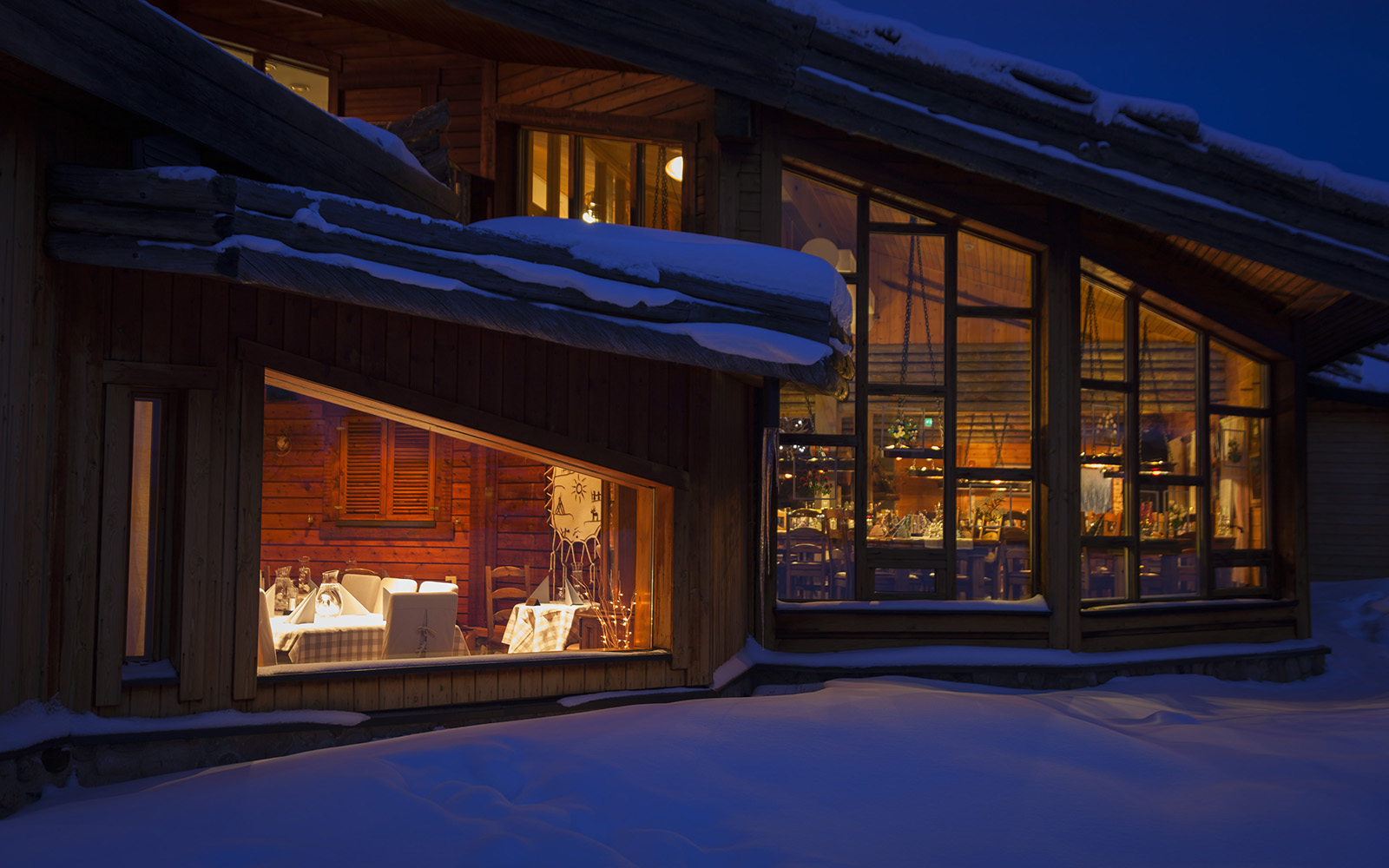 From outside, looking inside the cosy lit up restaurant at Hotel Yllas Humina in Akoslompolo, Finnish Lapland 
