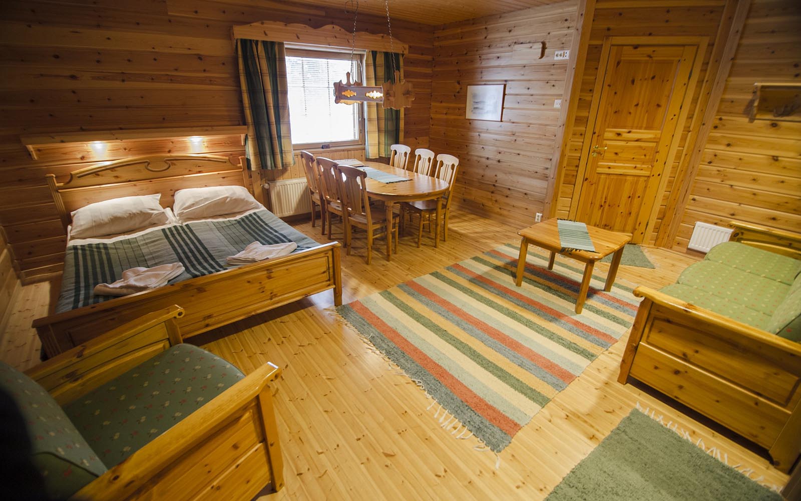 A more spacious pine clad Sauna Room at Harriniva Adventure Resort near Muonio in Finnish Lapland with double bed, sofa, arm chair and dining table