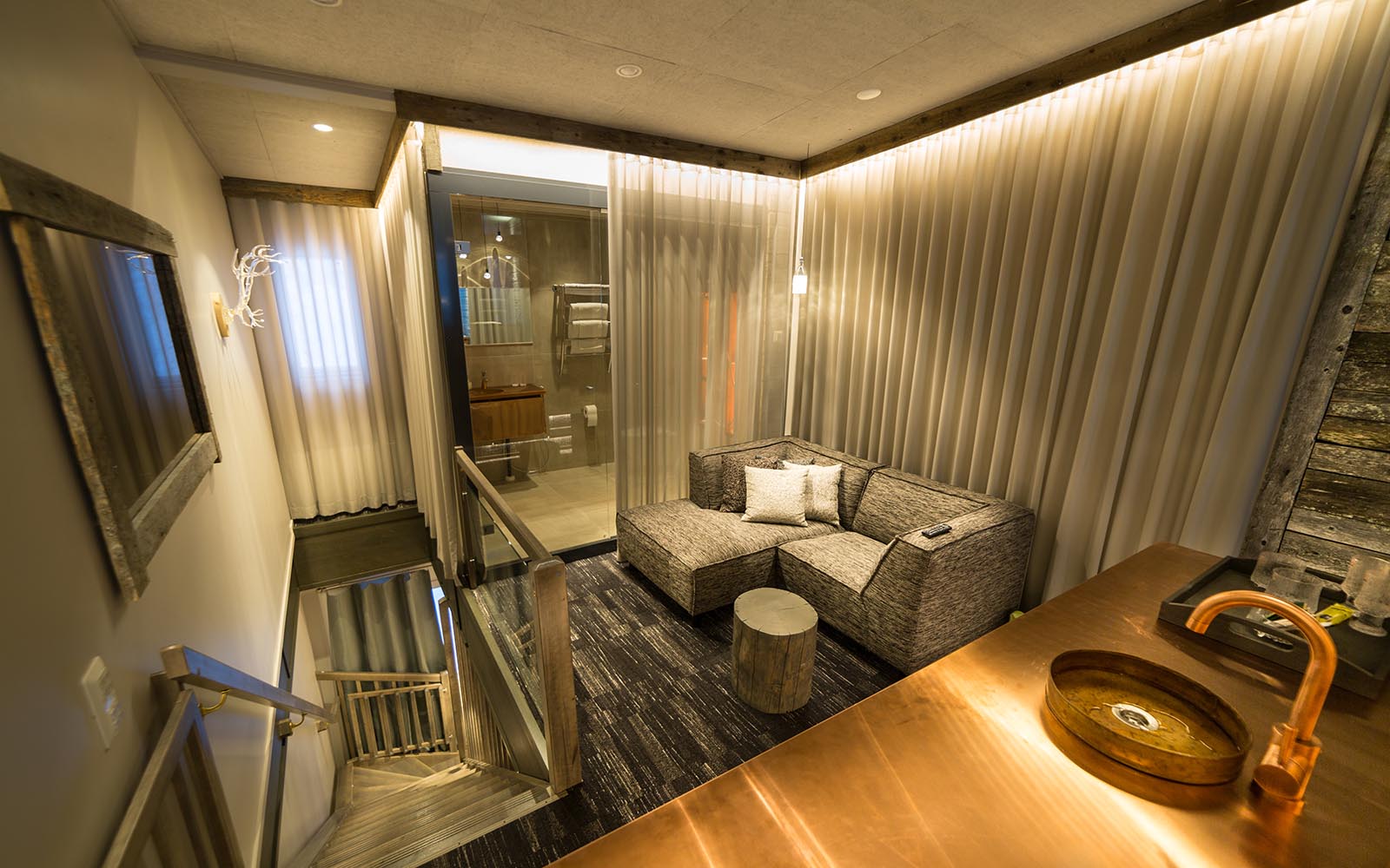 The upper level of the Aurora View Suite at Hotel Iso Syote show a corner sofa and bathroom beyond with a kitchenette in the foreground