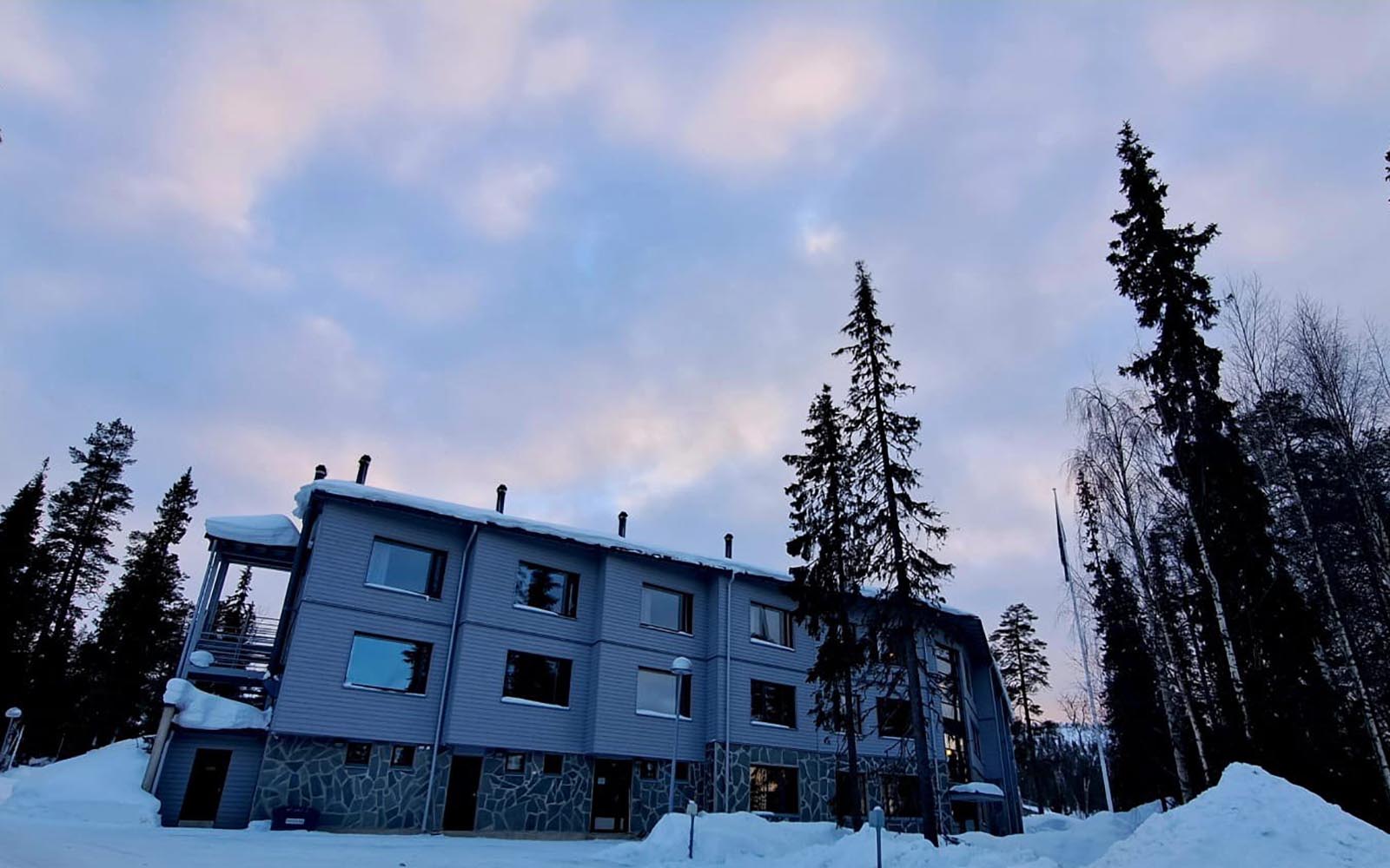 The stone and grey rendered exterior of Santa's Hotel Aurora in Luosto, Finnish Lapland shows the guest room windows facing north for Northern Lights viewing 