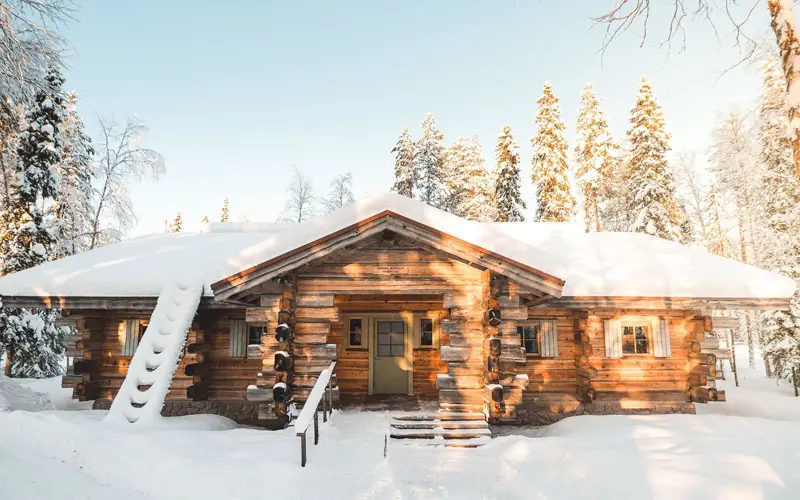 A traditional log cabin building covered in snow at Vaattunki Wilderness Resort near Rovaniemi in Lapland, Finland