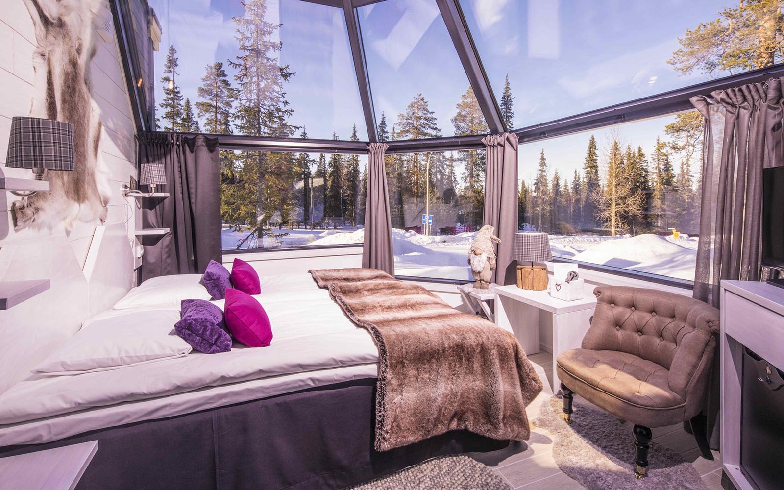 A premium Glass Igloo interior with a cosy bed situated under the glass ceiling at Santa's Hotel Aurora in Luosto, Finland 