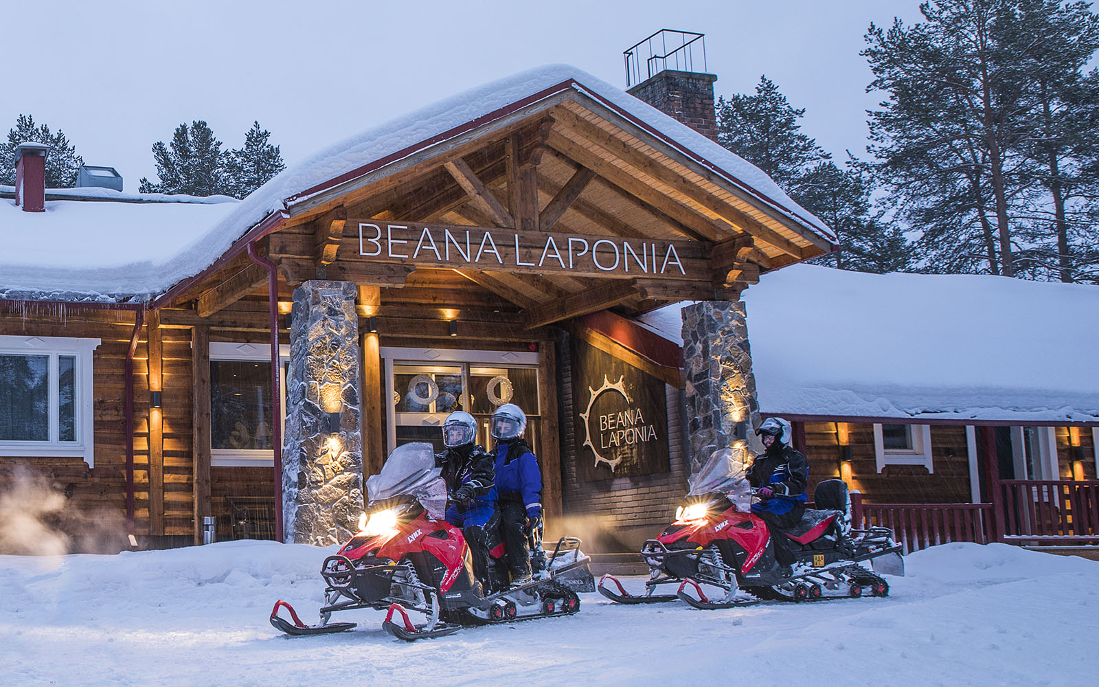 guests onboard two red snowmobiles at the entrance to Beana Laponia, a boutique hotel in Finnish Lapland 