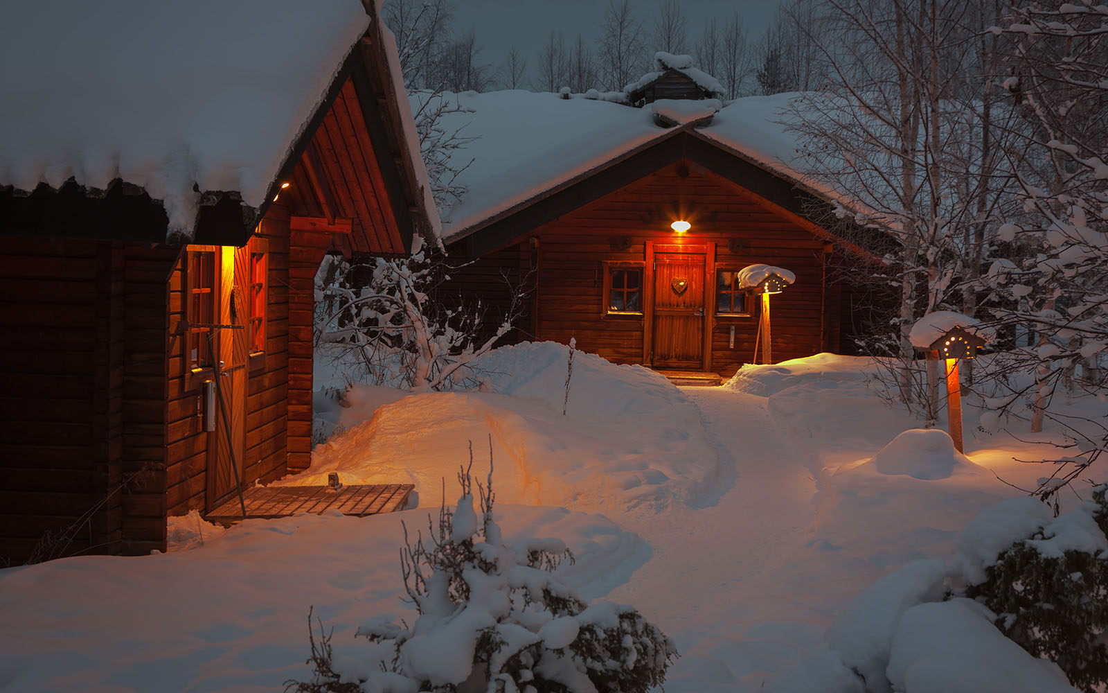A pathway carved into the snow leads to the rustic log buildings at Hotel Yllas Humina, each houses four hotel rooms offering comfortable accommodation for 2–5 people