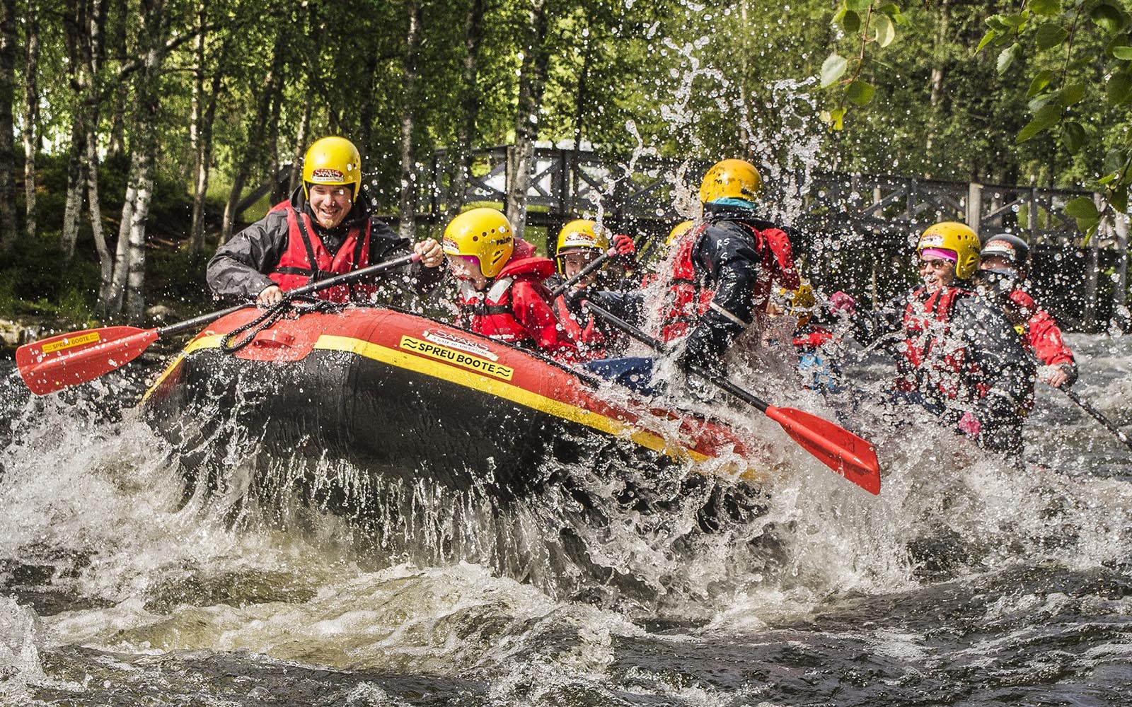 A groups of adventure seekers in an inflatable raft ride the seven wonderful rapids on river Kitka near Kuusamo, Finland