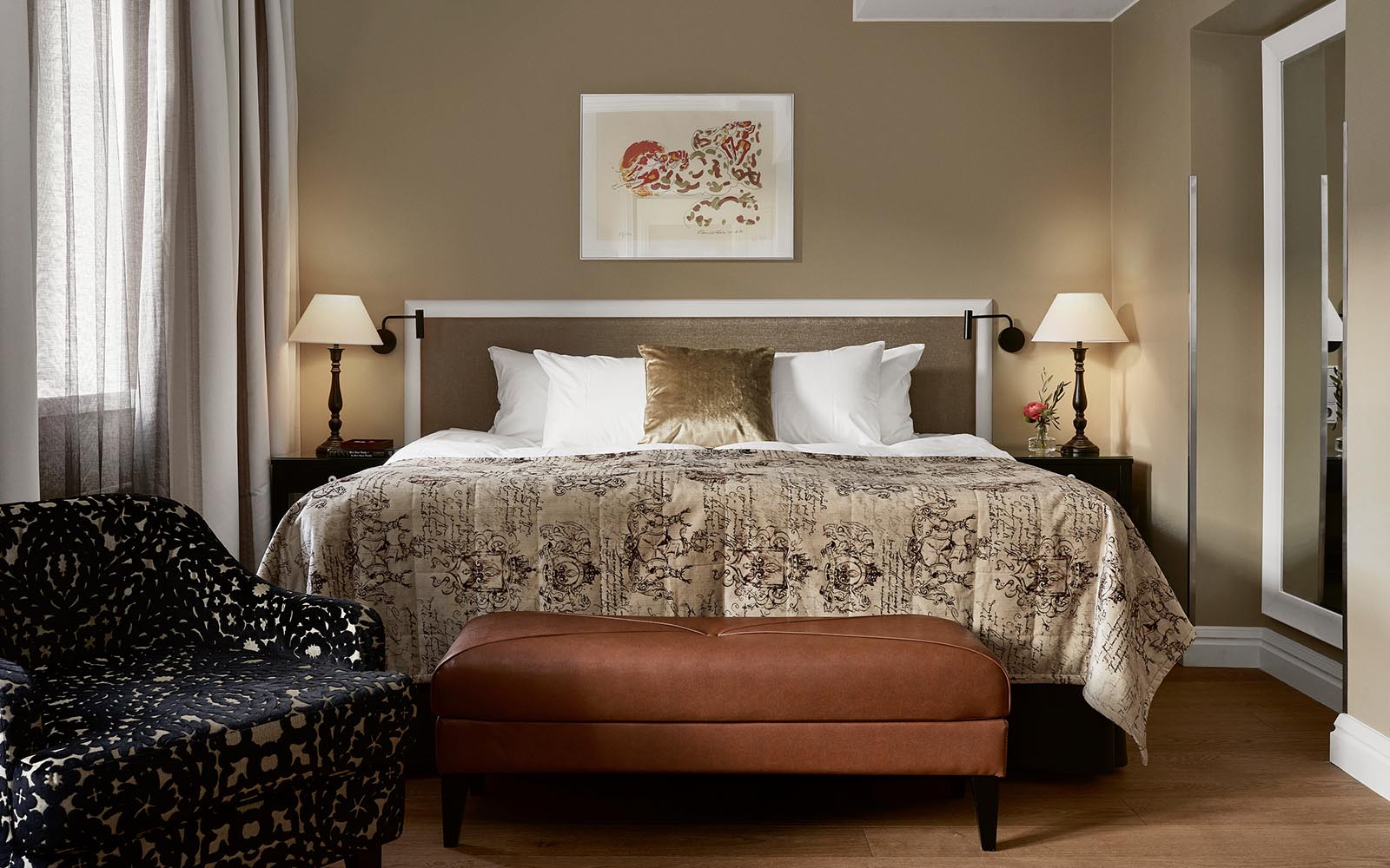 A superior guest room at Haven Hotel in Helsinki, Finland featuring a King bed, matching nightstands and an upholstered leather bench at the foot of the bed