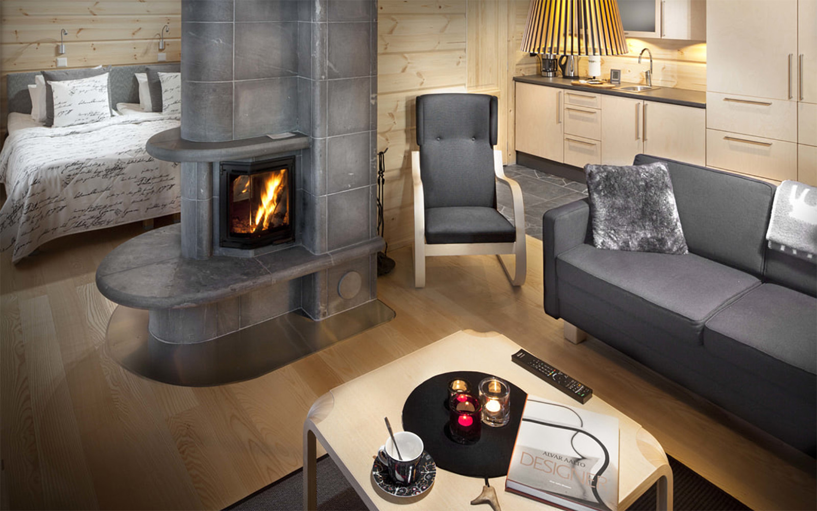 The open plan layout of the Superior Hotel Rooms at Hotel Yllas Humina, Finland.  The double aspect fireplace takes pride of place at the centre of the room, separating the living and sleeping quarters