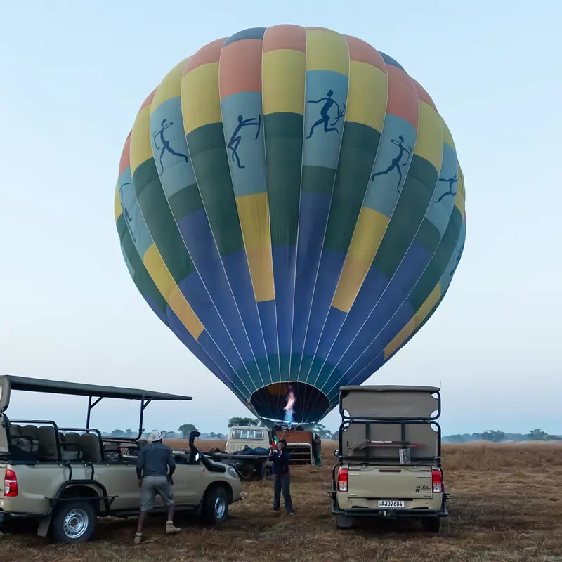 Hot air balloon being inflated behind safari vehicles at dawn on Busanga Plains, Kafue National Park; photograph taken on safari by Wildlife & Wilderness