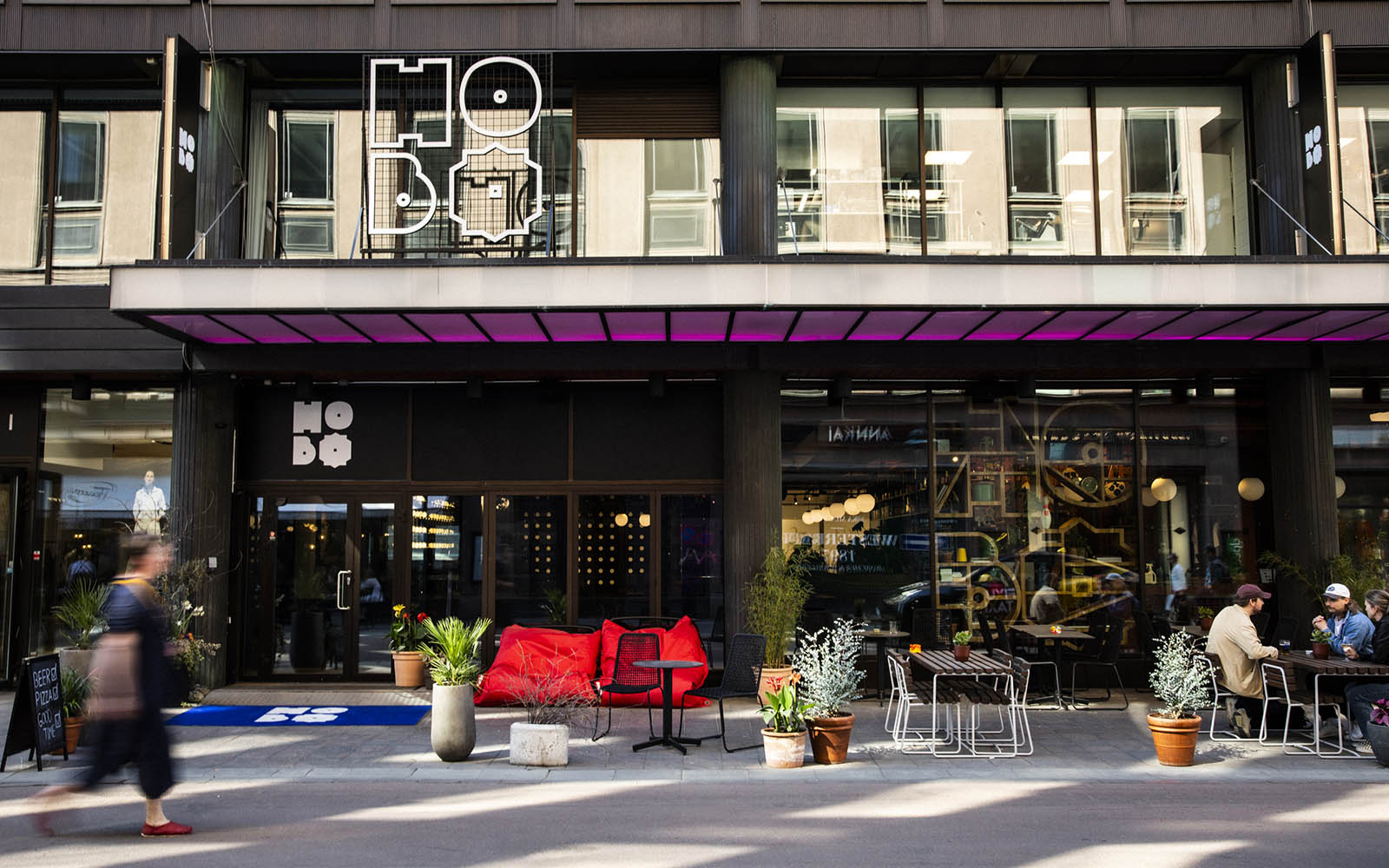 The fucky facade of Hobo Helsinki, a modern boutique hotel right at the heart of Helsinki, Kluuvikatu with pavement tables and comfy cushions